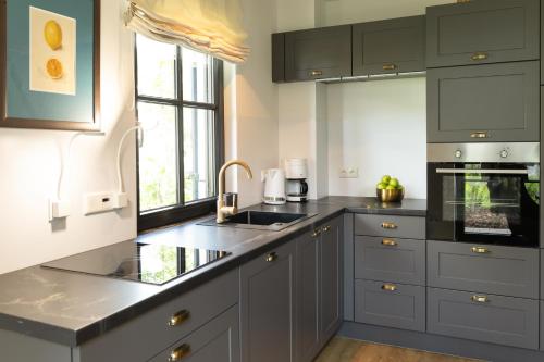 a kitchen with gray cabinets and a sink at Neues Friesenhaus Oogenstern Ferienhaus Usedom -stufenlos im Erdgeschoß- ruhige Lage in Zirchow