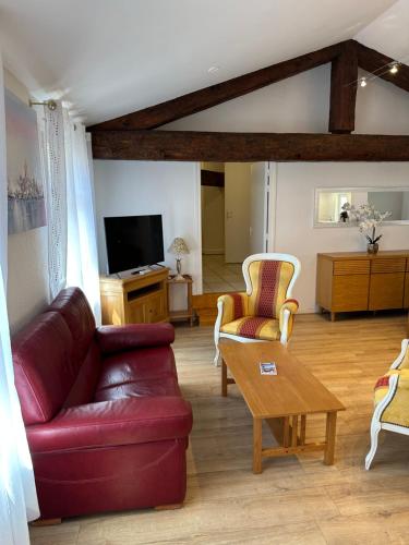 Maison du Cloitre Couvent des Carmes في ناربون: غرفة معيشة مع أريكة جلدية حمراء وكراسي