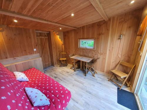 a room with a red bed in a wooden room at Cabane en bois sur l'étang in Landisacq