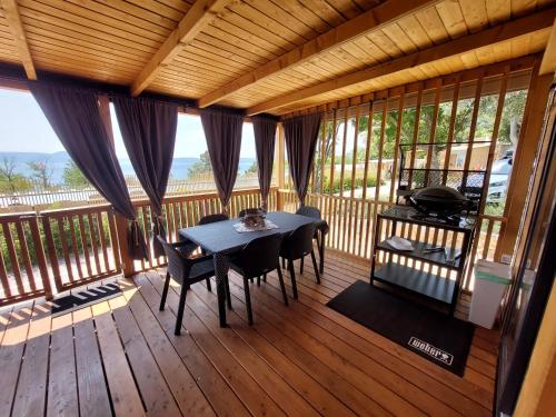a wooden deck with a table and chairs on it at MOBILE HOMES SELCE - ALPE JADRAN MOBIL 641 in Selce