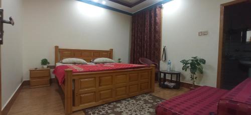 a bedroom with a large wooden bed with red sheets at Families Only! Eagle Nest Cottage Muzaffarabad by LMC in Muzaffarabad