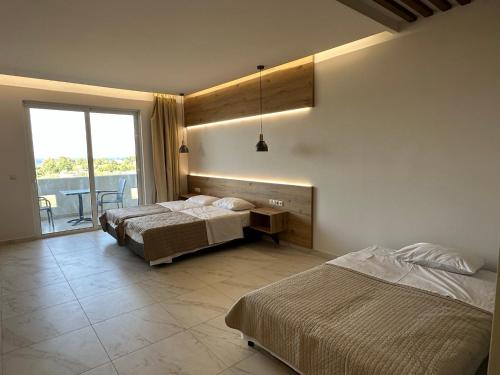 a bedroom with three beds and a table and a window at Faliraki Star in Faliraki