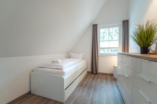 a white room with a white ottoman and a window at Ferienhaus Libelle in Zirchow