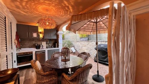 uma cozinha com uma mesa e cadeiras e um guarda-sol em Chez Virginie em Porto-Vecchio
