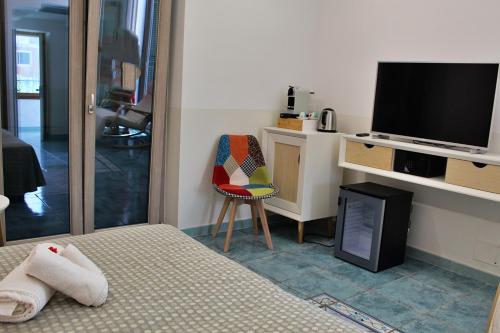 una camera con letto, TV e sedia di Hotel Lo Smeraldo a Ventotene