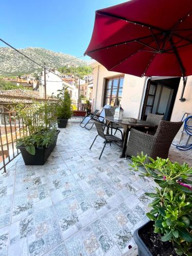 a patio with a table and a red umbrella at Lykovrisi Guest House in Arachova