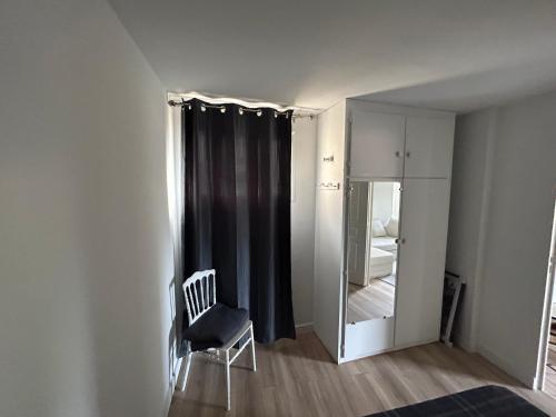 ein weißes Zimmer mit einem Stuhl und einem Spiegel in der Unterkunft appartement quai de la Fontaine in Nîmes