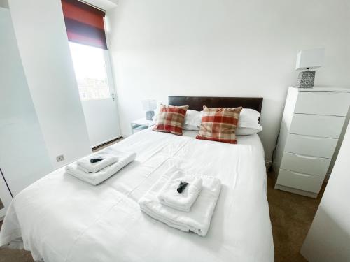 Un dormitorio con una cama blanca con toallas. en Pipelands Road, en St Andrews