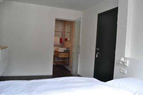 a bedroom with a white bed and a bathroom at PANACHE - BIKE EN SLEEP HOTEL in La Roche-en-Ardenne