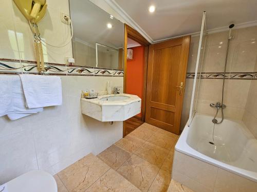 a bathroom with a tub and a sink and a shower at Hotel Rural Casa Migio in Urbiés