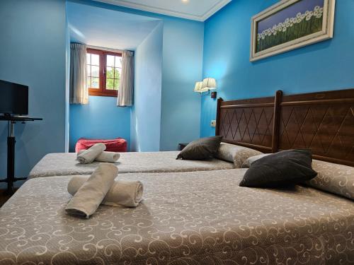 two beds in a bedroom with blue walls at Hotel Rural Casa Migio in Urbiés
