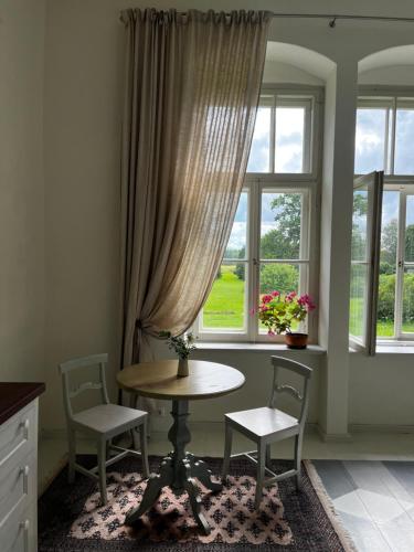 a room with a table and two chairs and a window at Oleru muiža in Oleri