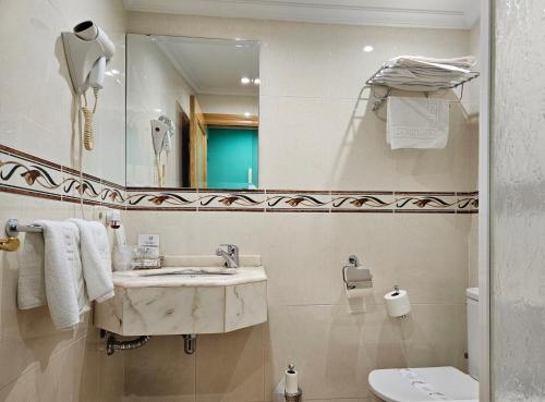 a bathroom with a sink and a mirror and a toilet at Hotel Rural Casa Migio in Urbiés