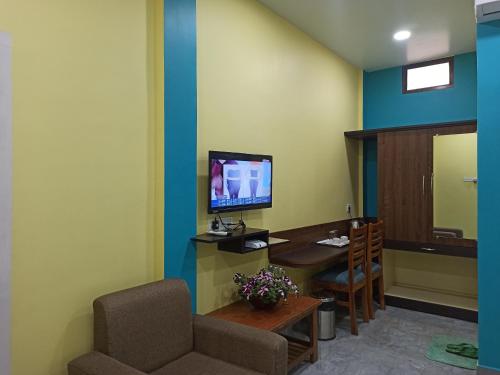 a room with a desk and a tv and a chair at Atithya Resort in Khānāpāra