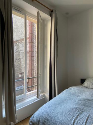 a bedroom with a bed and a window at Studio quai de Valmy in Paris