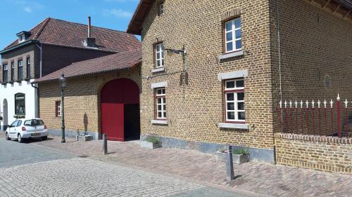 een bakstenen gebouw met een rode deur op een straat bij Boerderijwoning Elsloo in Elsloo