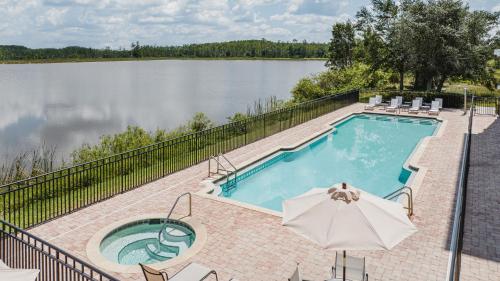 uma piscina com um guarda-sol junto a um lago em Crowne Plaza Ft Myers Gulf Coast, an IHG Hotel em Fort Myers