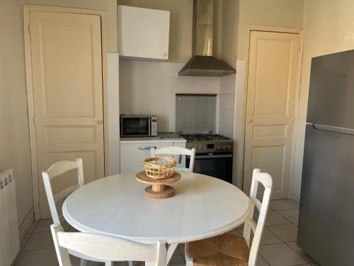 une petite cuisine avec une table et des chaises blanches dans l'établissement Alberta, à Béziers