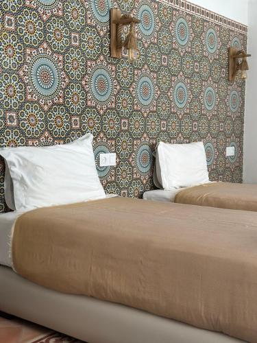 2 bedden in een hotelkamer met een muur bij Riad Al Zahia in Essaouira