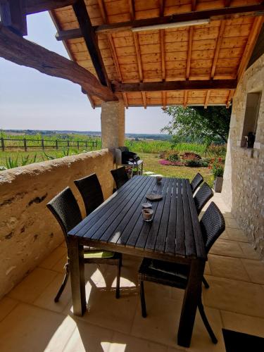 une table et des chaises en bois sur une terrasse dans l'établissement Gîte de charme dans un cadre calme et reposant, à Châtellerault