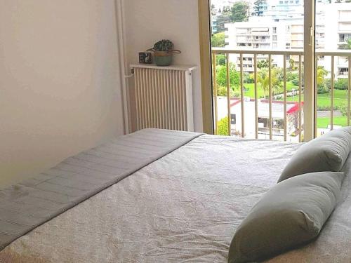 un lit dans une chambre avec une grande fenêtre dans l'établissement Vue mer sublime - Piscine & activités sur place, à Juan-les-Pins