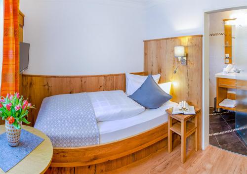 a bedroom with a bed with a wooden headboard and a table at Glashotel in Zwiesel