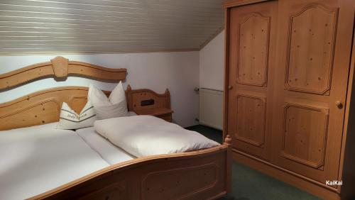 sypialnia z dużym białym łóżkiem z drewnianym zagłówkiem w obiekcie Erd´s Hoimatle w mieście Jungholz