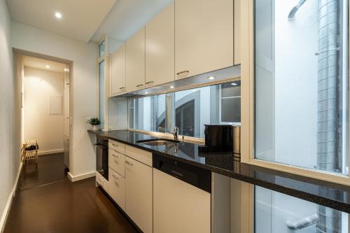 a kitchen with white cabinets and a black counter top at Historische Wohnung im Herzen der Thuner Altstadt in Thun