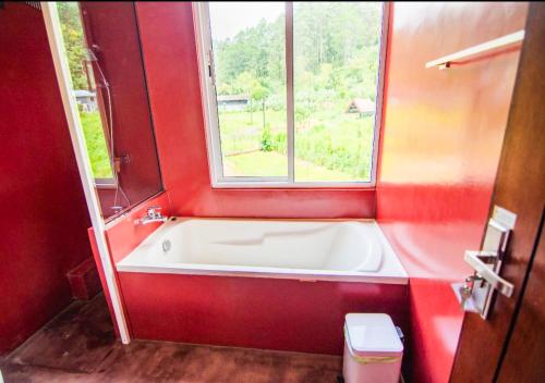 a bath tub in a red bathroom with a window at Serenemo Eco Resort in Pundaluoya