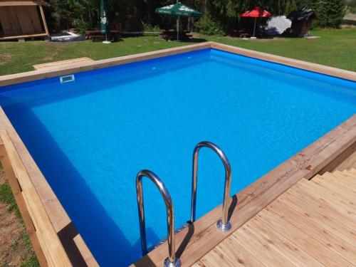 a blue swimming pool with metal railings in a yard at Olza Karczma i pokoje in Istebna