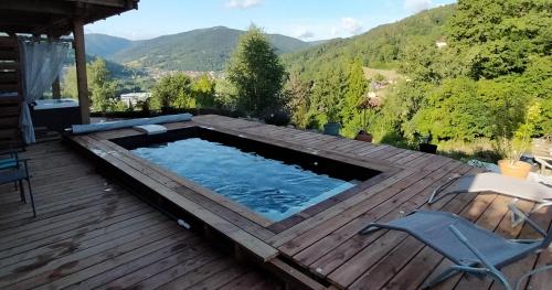 a swimming pool on a deck with mountains in the background at Au chalet de JO avec accès à l'espace piscine et jacuzzi in Muhlbach-sur-Munster