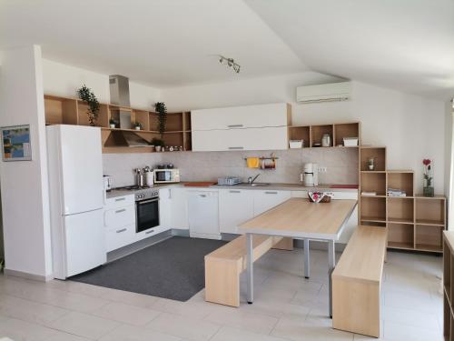 a kitchen with white cabinets and a wooden table at Apartments Permida in Dramalj