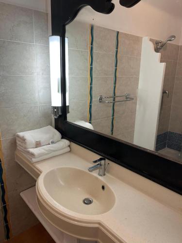 a bathroom with a sink and a mirror and towels at Studio avec vue mer exceptionnelle, plage et piscine, Village Vacances Sainte-Anne in Sainte-Anne