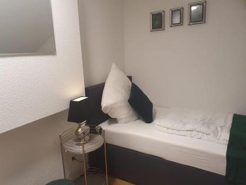um pequeno quarto com uma cama com lençóis brancos e almofadas em Waterfalls Apartment em Triberg