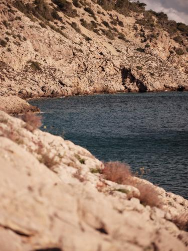 a large body of water next to a rocky mountain at Mondrian Ibiza in Cala Llonga