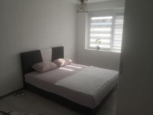 a bed with two pillows in a bedroom with a window at Apartman Nea in Sanski most