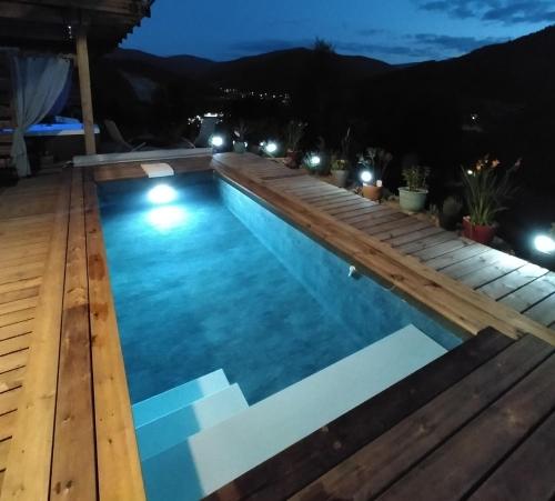 a swimming pool at night with a wooden deck at Au chalet de JO avec accès à l'espace piscine et jacuzzi in Muhlbach-sur-Munster