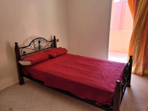 a bedroom with a bed with a redspread and a window at Duplex avec piscine - Sidi Bouzid in El Jadida