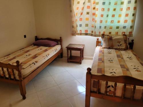 a bedroom with two beds and a table and a window at Duplex avec piscine - Sidi Bouzid in El Jadida
