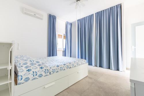 ein weißes Schlafzimmer mit blauen Vorhängen und einem Bett in der Unterkunft Villa Cirenaica in Torre Ovo