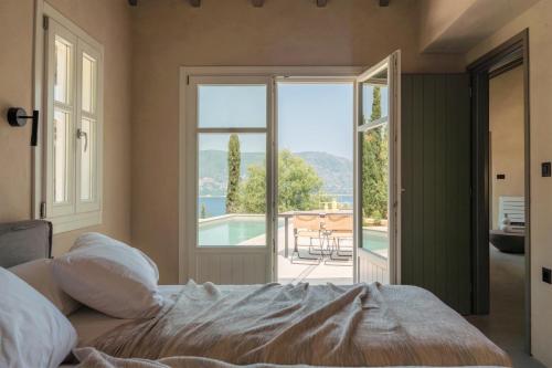 een slaapkamer met een bed en uitzicht op een zwembad bij F Topia Villas in Fiskardho