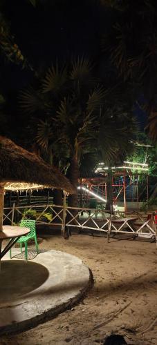 a beach at night with a green bench and palm trees at Wild Dunes Konark in Bālighāi