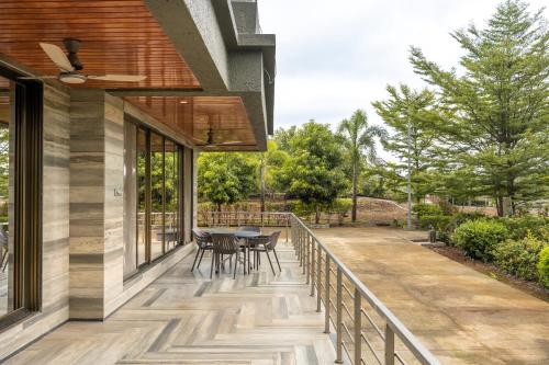 a deck with a table and chairs on a house at SaffronStays Siesta by the River in Murbād