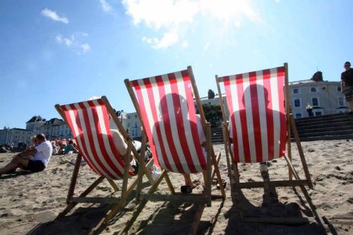 three chairs sitting in the sand on the beach at Cludfan (Cosy Place) - in the heart of Llandudno in Llandudno
