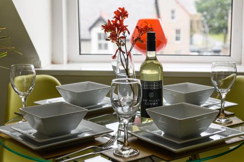 a table with a bottle of wine and glasses on it at Cludfan (Cosy Place) - in the heart of Llandudno in Llandudno