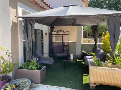 une terrasse avec un parasol, des chaises et des plantes dans l'établissement studio au calme pres des plages, à Six-Fours-les-Plages