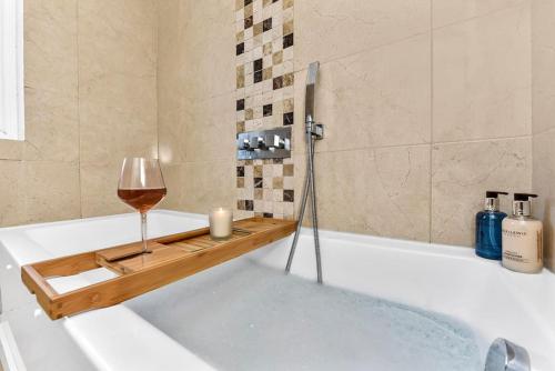 a bath tub with a glass of wine and a candle at 3BR home/Fast Wi-Fi/ Quiet road in Hither Green