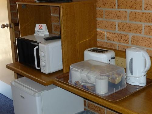 a counter with a microwave and other appliances on it at Royal Palms Motor Inn in Coffs Harbour