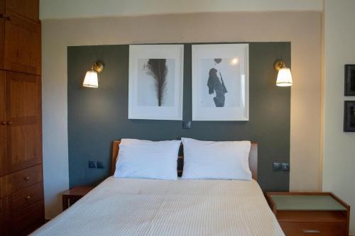 a bedroom with a bed with three pictures on the wall at Αλσύλλιο - Alsillio studio apartments in Ierissos
