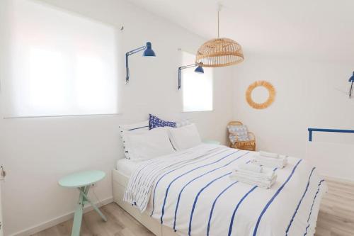 a white bedroom with a bed with blue and white stripes at duArteLoft in Sines